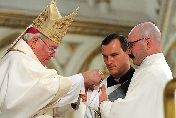 After anointing his hands with Holy Oil Bishop Richard J. Malone wraps the hands of Father Peter Santandreu during a Mass at St. Joseph Cathedral where four men were ordained into the priesthood. (Dan Cappellazzo/Staff Photographer)